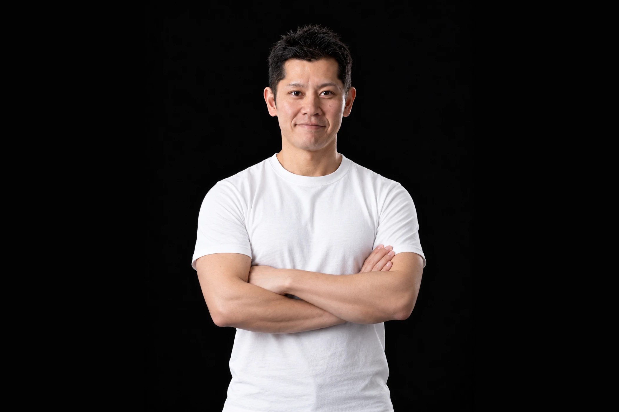 白いTシャツで腕を組んで立つ、GAMO fitnessのトレーナー