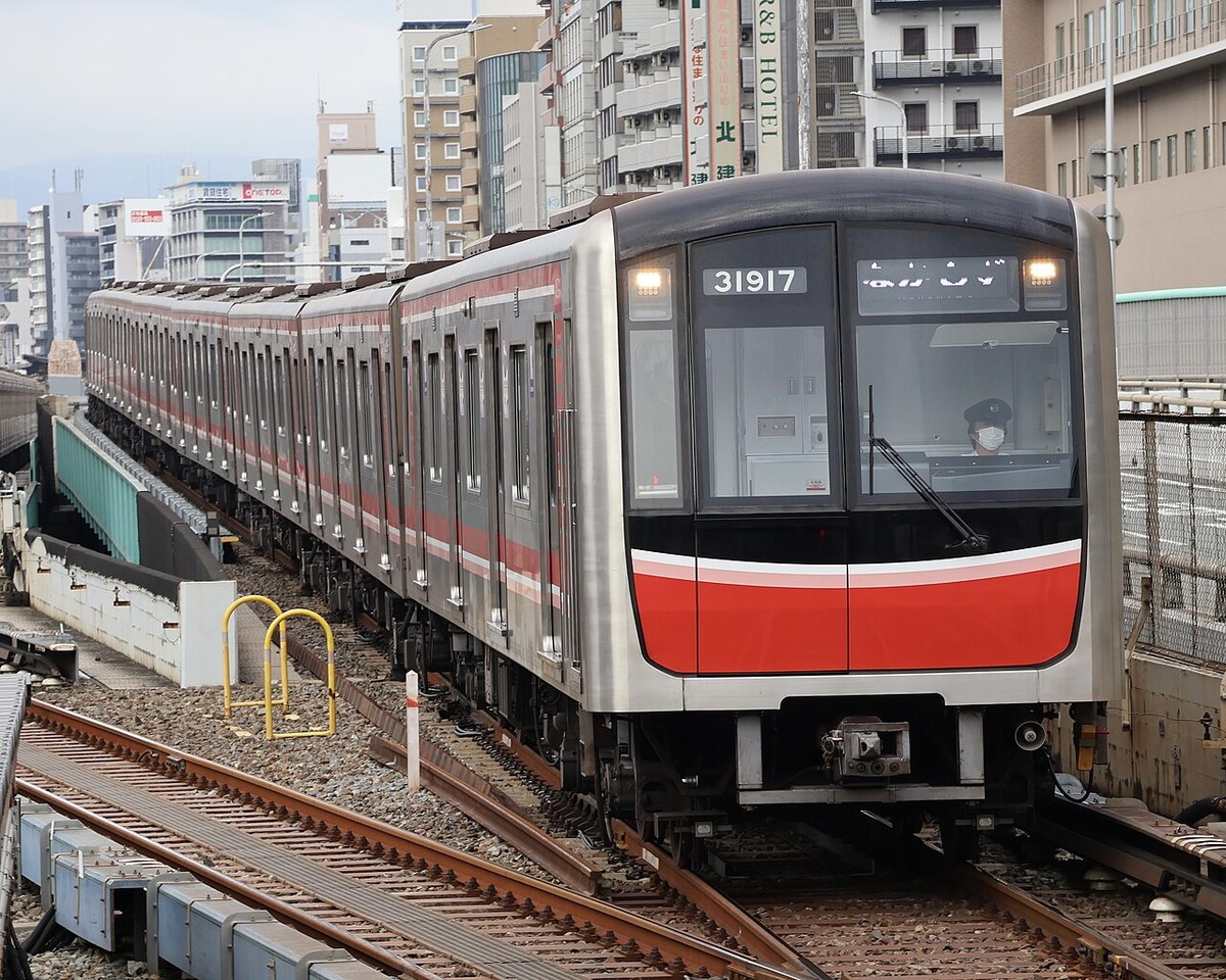 新大阪駅の地上区間を走るOsaka Metro御堂筋線の電車（銀色の車体に赤い帯）